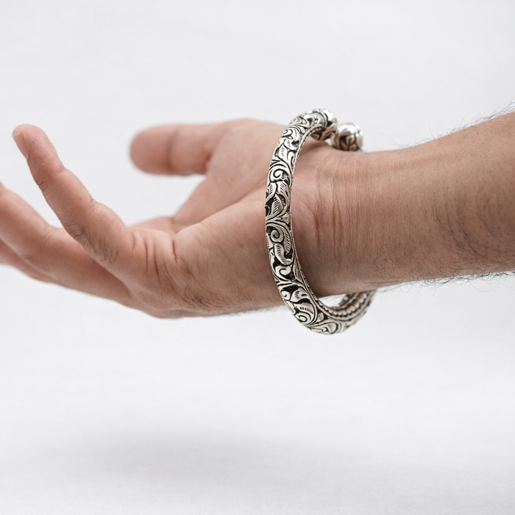 Hand wearing a silver bracelet on a light gray background