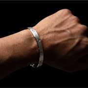 Silver bracelet on a wrist against a black background